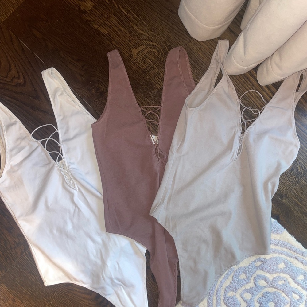 Three bodysuits from Aritzia (sizes shown on tags)